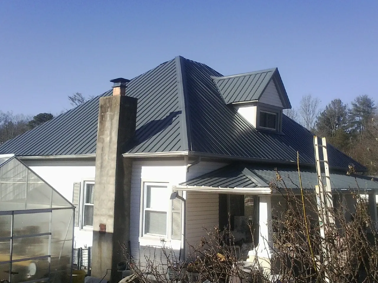 Dark blue standing seam metal roof on a white farmhouse with dormer — Slate & Tile Roof Repair by Roofing Brothers in Pink Hill
