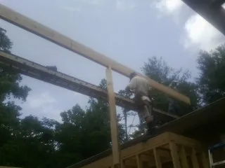 Carpenter setting a ridge beam over a new addition frame — Ice Dam Removal by Roofing Brothers in Pink Hill