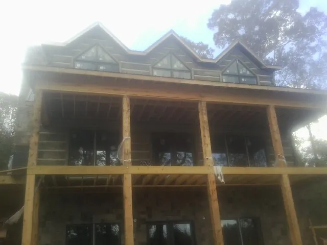 Dormers and porch framing on a large log home under construction — Roof Coating work by our crew in Pink Hill