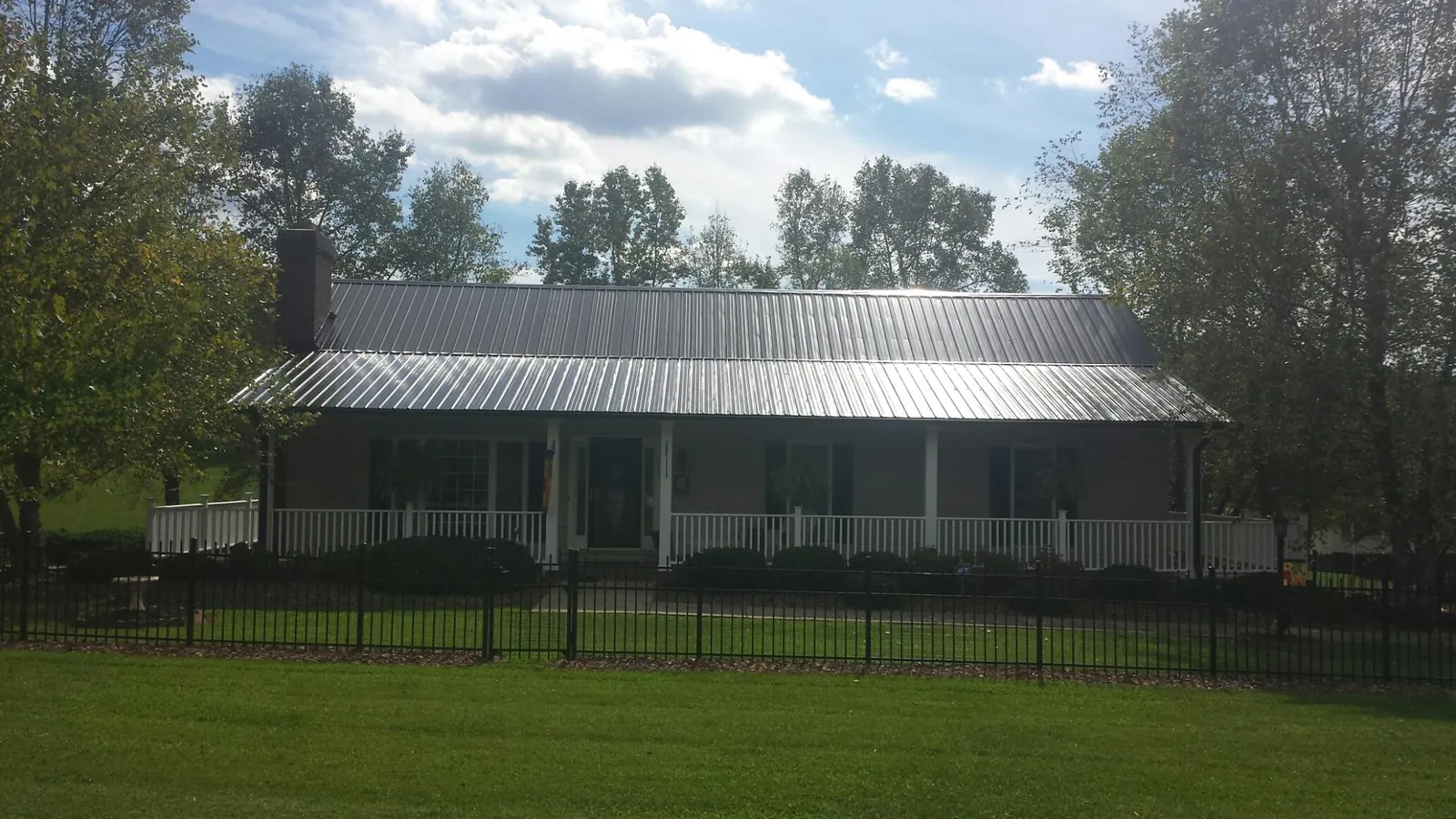 Gray metal roof on a brick ranch with a full width front porch — Gutter Guard Installation work by our crew in Pink Hill