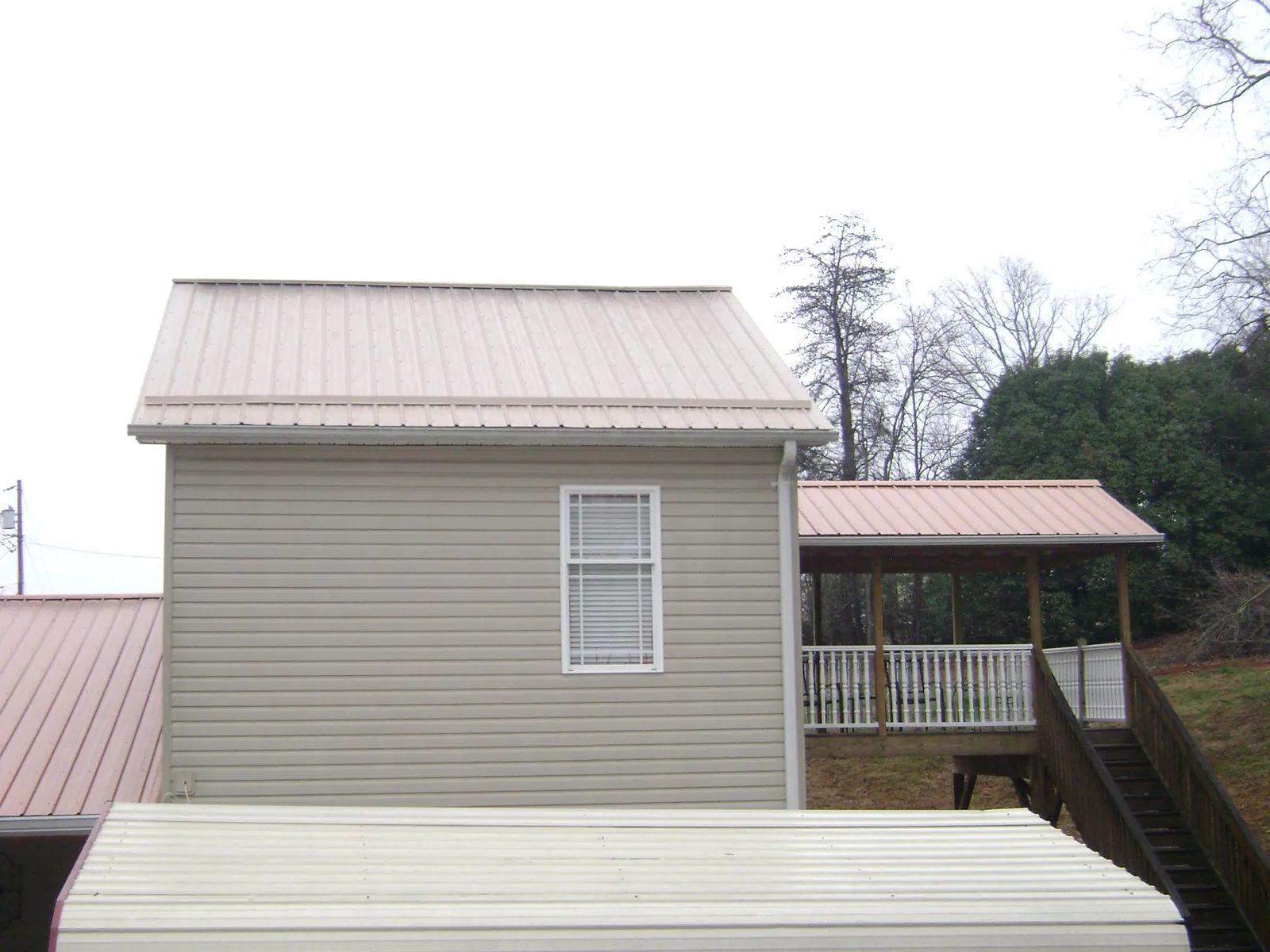 Tan metal roofs on a two story addition and attached porch, from a Roof Replacement job in Pink Hill