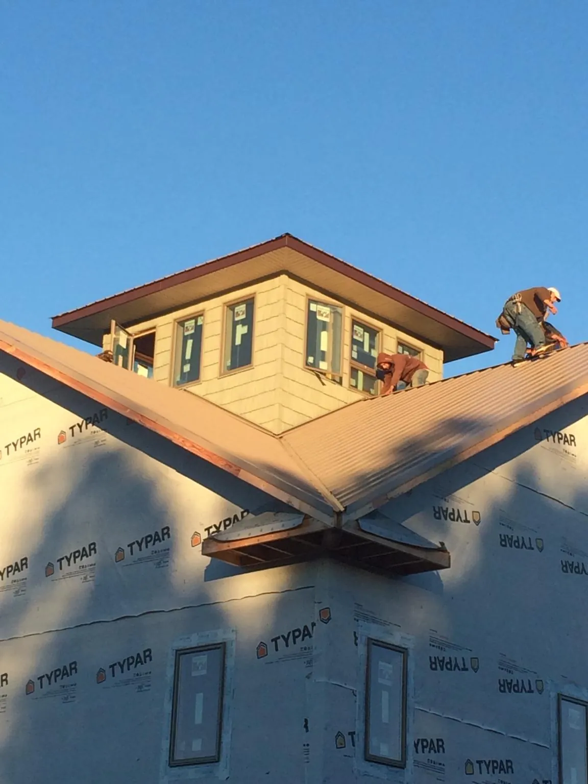 Roofers working around a rooftop cupola on a new metal roof at sunset — Roof Waterproofing in Pink Hill by Roofing Brothers